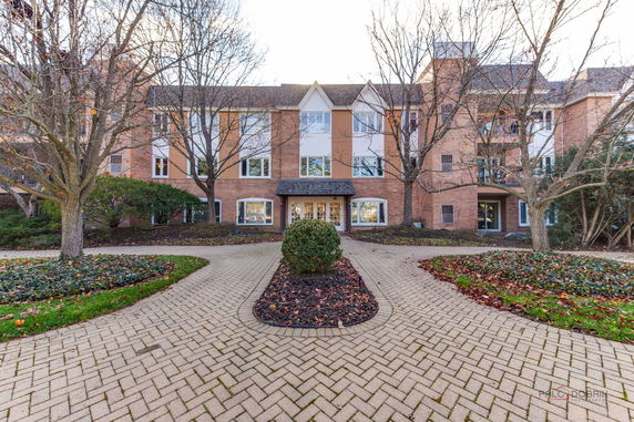 Front view of a multi-story brick building with trees and a paved walkway.