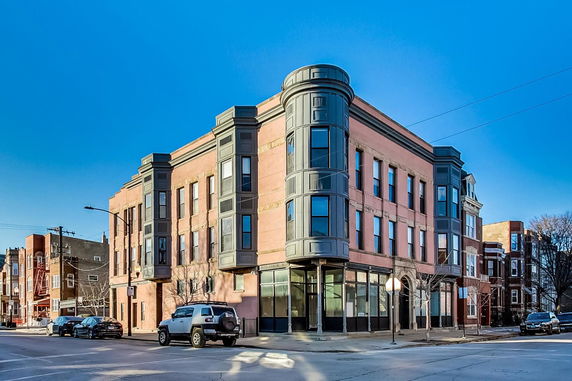 Front view of a multi-story brick building with rounded corner windows.