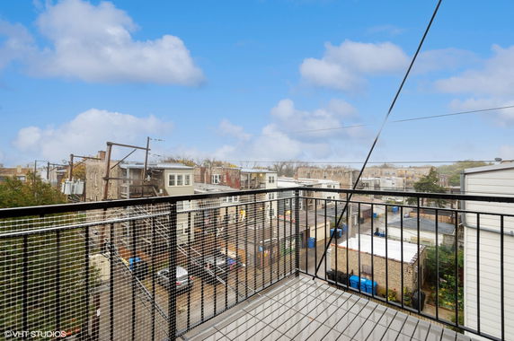 Panoramic view from a rooftop balcony overlooking a residential area with buildings and clear skies.