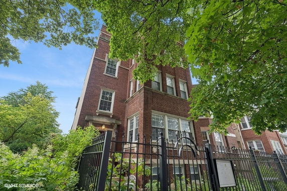 Front view of a multi-story brick building with decorative windows and an iron fence.