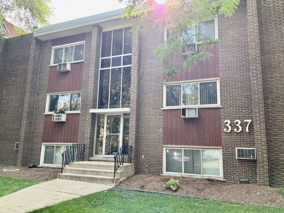 Front view of a multi-story building with a brick facade and large windows.