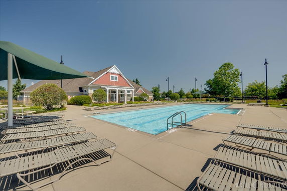 Outdoor swimming pool area with lounge chairs and adjacent building.
