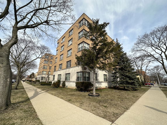 Front view of a multi-story brick building with large windows.