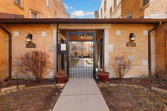 Front view of a brick building with a gated entrance and pathway.