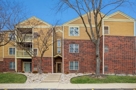 Front view of a multi-story brick and siding apartment building.