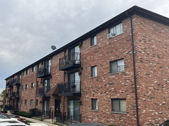 Front view of a multi-story brick apartment building with balconies.