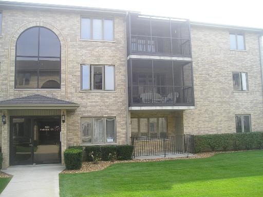 Front view of a three-story apartment building with balconies and large windows.