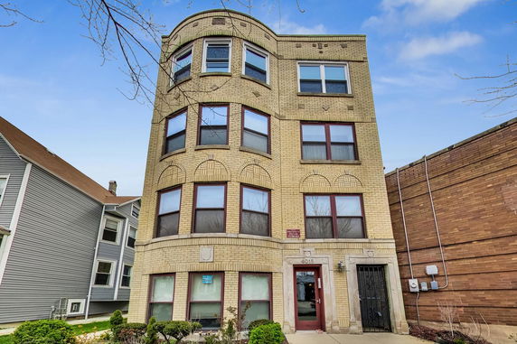 Front view of a four-story brick building with rounded corners and multiple windows.