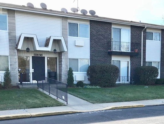 Front view of a two-story apartment building with balconies and a central entrance.