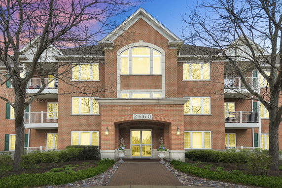 Front view of a multi-story brick building with balconies and large windows.
