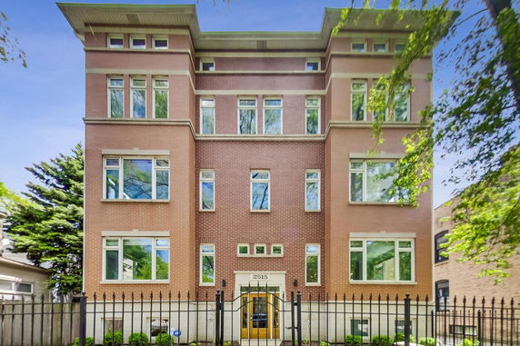 Front view of a multi-story brick building with multiple windows and a gated entrance.