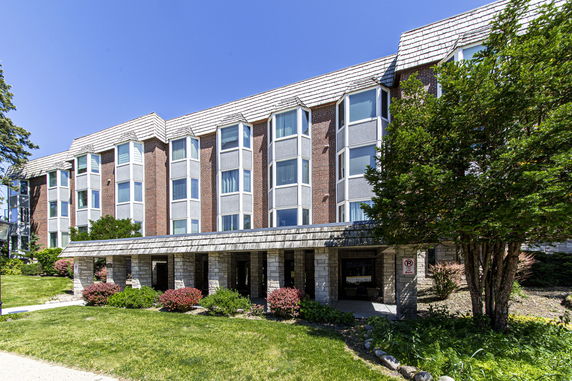 Front view of a three-story building with large windows and brick facade.