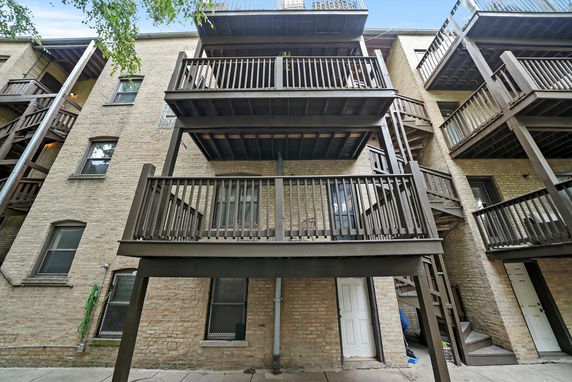 Rear view of a multi-story apartment building with wooden balconies and staircases.
