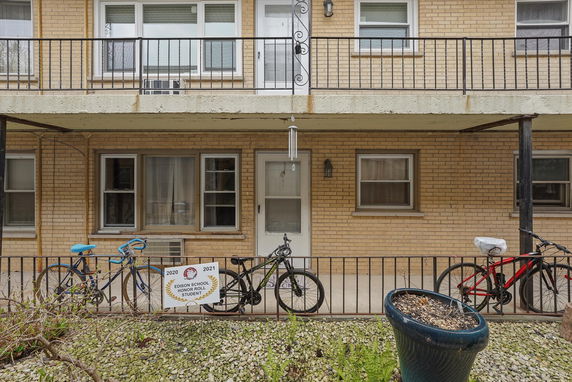 Front view of a two-story building with balcony and bicycles parked outside.