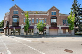 Front view of a multi-story brick building with retail spaces on the ground floor.