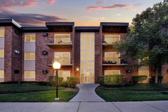 Front view of a multi-story brick apartment building with balconies.