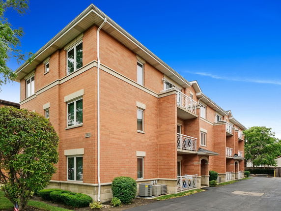 Front view of a multi-story brick apartment building with balconies.