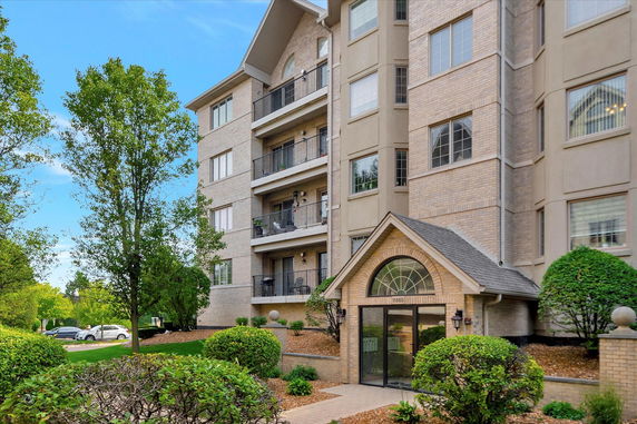 Front view of a multi-story residential building with balconies and a glass entrance.