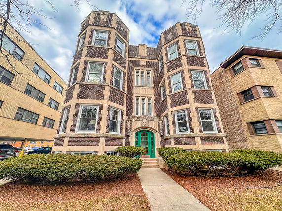 Front view of a multi-story brick building with a decorative entrance.