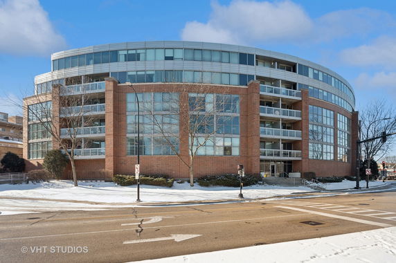Front view of a curved multi-story building with large windows and balconies.