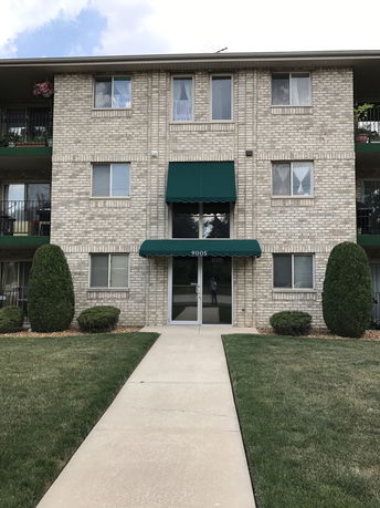 Front view of a three-story brick building with green awnings.