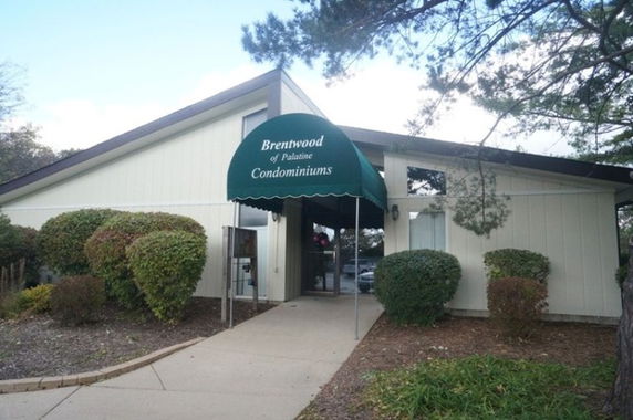 Front view of a building with a green canopy entrance labeled 'Brentwood of Palatine Condominiums'.