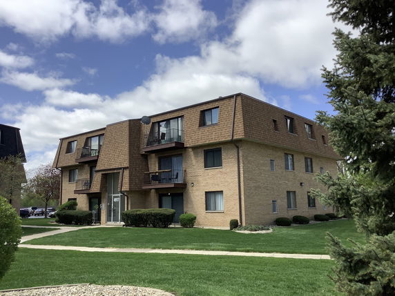 Front view of a two-story brick apartment building with balconies.