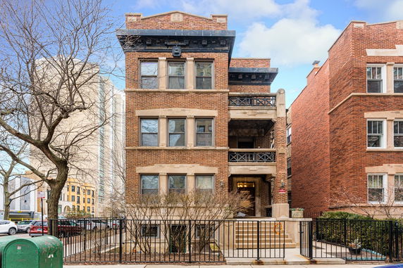 Front view of a three-story brick residential building with balconies.