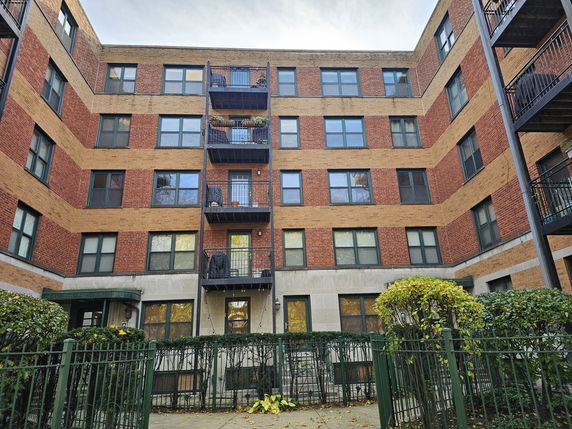 Front view of a multi-story brick apartment building with balconies.