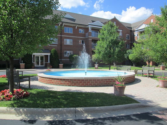 Front view of a multi-story brick building with a fountain in front.
