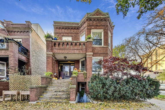 Front view of a two-story brick house with decorative elements and a stairway entrance.