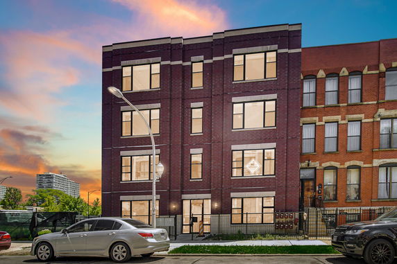 Front view of a multi-story brick building with large windows.