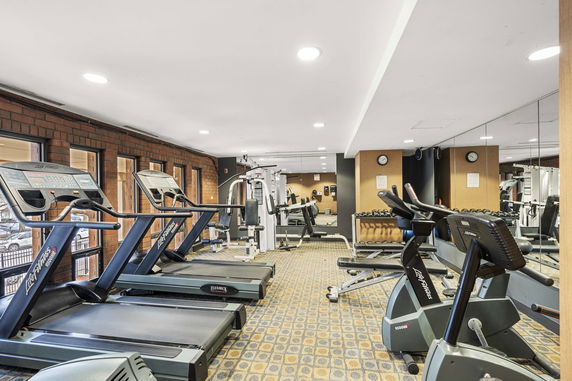 Indoor gym area with treadmills, exercise bikes, and workout equipment.