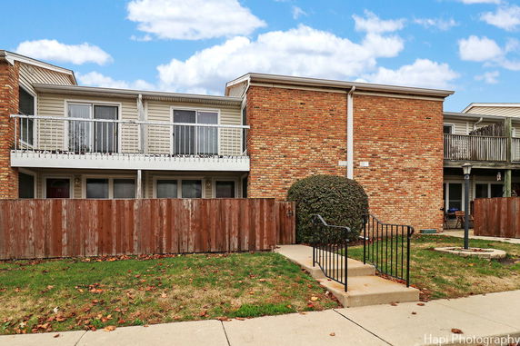 Front view of a residential building with balconies and a brick facade.