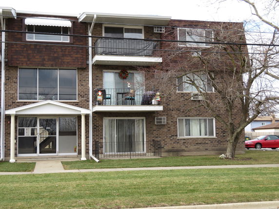 Front view of a multi-story apartment building with balconies and a front entrance.