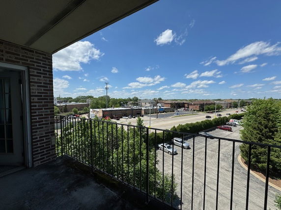 Panoramic view from a balcony overlooking a parking area and surrounding buildings.