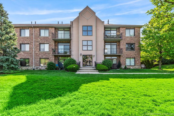 Front view of a three-story apartment building with brick exterior and balconies.