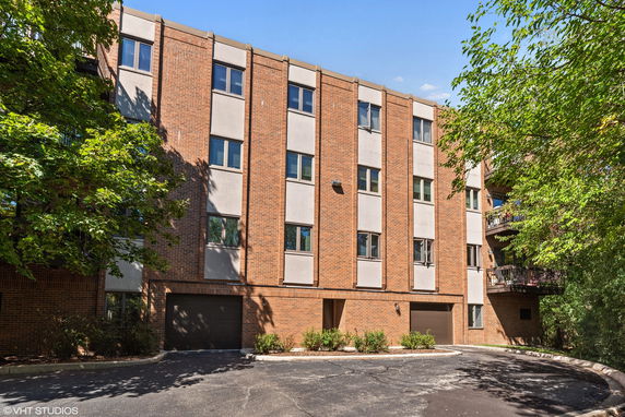 Front view of a multi-story brick building with multiple windows and garage entrances.
