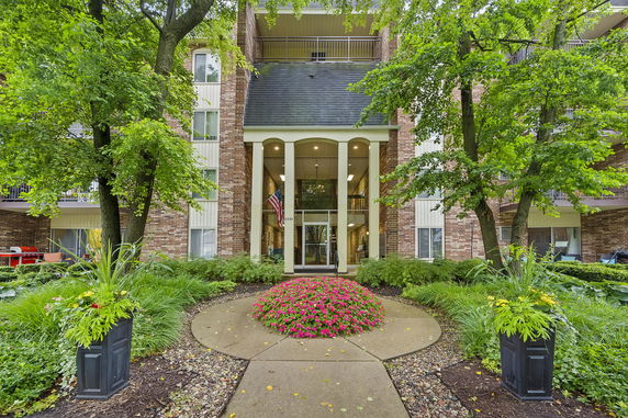 Front view of a multi-story brick apartment building with columns and an entrance.