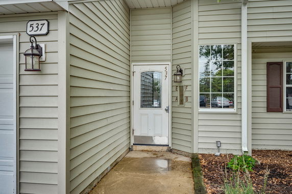 Front view of a house with light-colored siding and a white door.