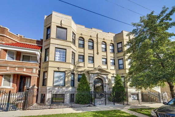 Front view of a multi-story residential building with arched windows and a decorative entrance.