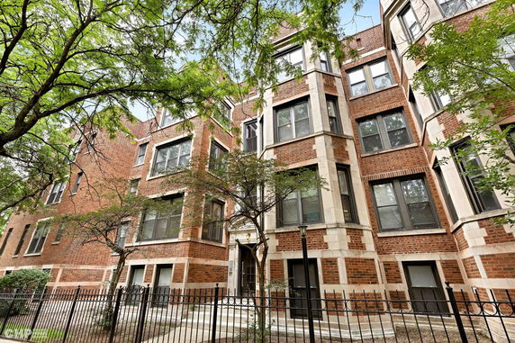 Front view of a multi-story brick building with large windows and an entrance.