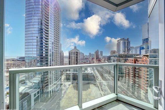 Panoramic view from a balcony showing a city skyline with tall buildings and a blue sky.