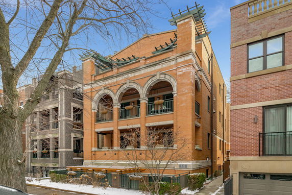 Front view of a multi-story brick building with arches and balconies.