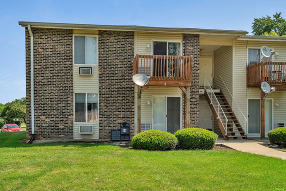 Front view of a two-story brick apartment building with balconies and external stairs.