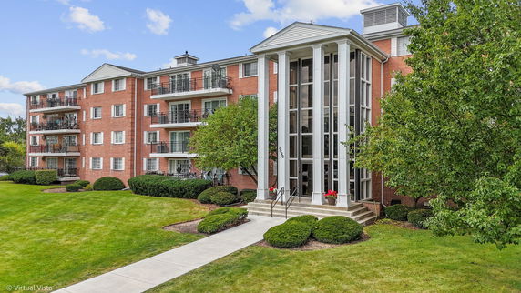 Front view of a multi-story brick apartment building with balconies.