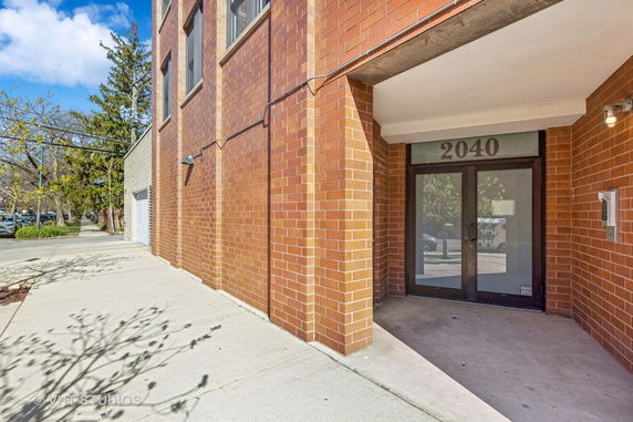 Front view of a brick building entrance with glass doors.