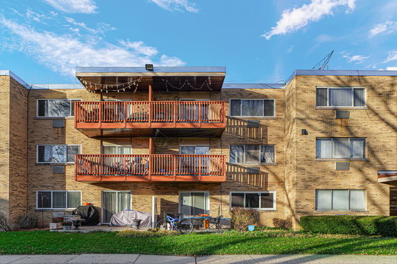 Front view of a multi-story brick apartment building with balconies.