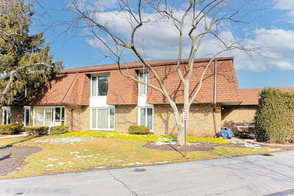 Front view of a two-story house with a brick facade and brown roof.