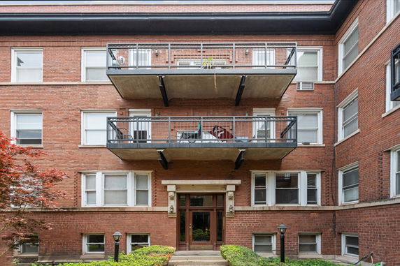 Front view of a multi-story brick apartment building with balconies.